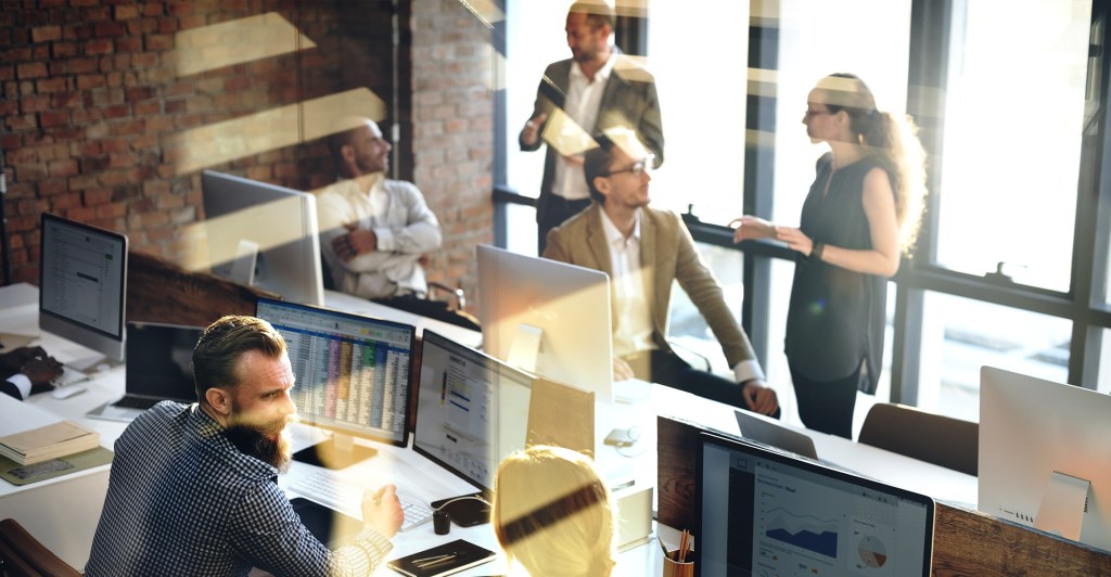 company-mission-drknd workers conversing in a modern open office